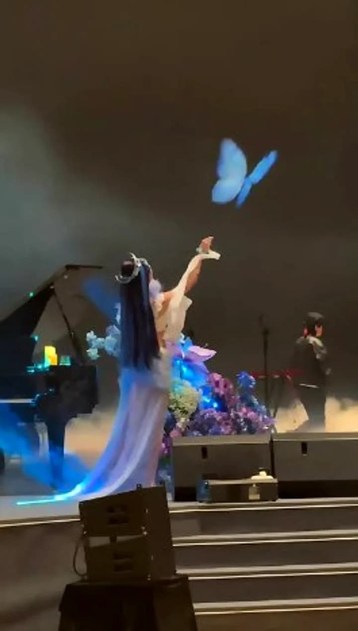 A blue Titli butterfly rising from a performer on stage